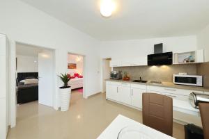 a kitchen with white cabinets and a bed in a room at Apartments ROSINI, 300m from the beach with shared tavern and bikes, Nin in Nin