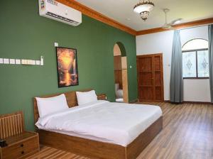 a bedroom with a large bed with a green wall at Saal house in Nizwa +16 photos