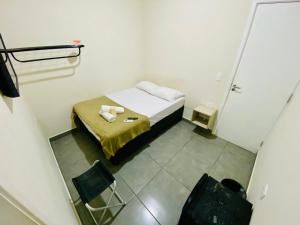 a small room with a small bed and two chairs at Pousada Nosso Lar - Opte sem ou com Café, Estacionamento e a uma Quadra da Praia in Guarujá