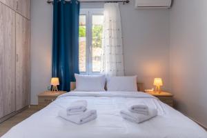 a bedroom with a large white bed with two towels on it at Deep Blue Escape Villa Salamina in Áyios Yeóryios