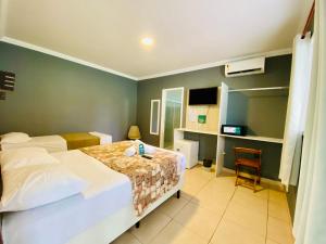 a bedroom with a bed and a desk in it at Pousada Nosso Lar - Opte sem ou com Café, Estacionamento e a uma Quadra da Praia in Guarujá