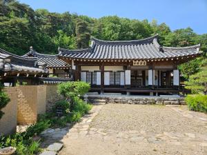 an asian style building in a garden with trees at Tohyang Traditional House in Bonghwa