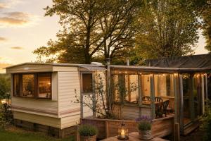 a tiny house with a wrap around porch at Rustig Chalet Ardennen The Forest Haven in Amblève +10 photos