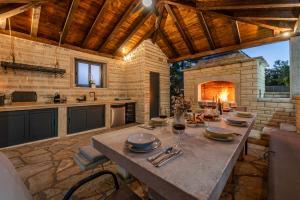 a large kitchen with a table and a fireplace at Villa Balen ZadarVillas in Lisičići