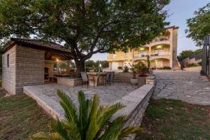 a patio with a table and chairs under a tree at Villa Balen ZadarVillas in Lisičići
