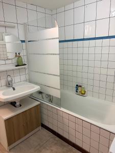 a white tiled bathroom with a sink and a tub at Calm guest house in Clerval
