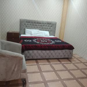ein Bett mit grauem Kopfteil und ein Stuhl in der Unterkunft River Breeze Hotel in Mingora
