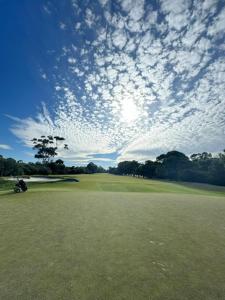 a view of a golf course with a cloudy sky at 10-Min Walk to Pearce Beach via Coastal Trail in Blairgowrie