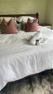 a bed with white sheets and pillows on it at Indaba tree lodge in Bulawayo