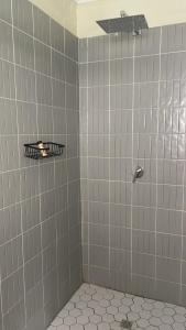 a bathroom with a shower with white tiles at Indaba tree lodge in Bulawayo
