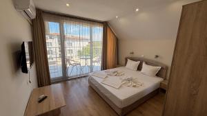 a bedroom with a bed and a large window at Семеен хотел Сирена in Ahtopol
