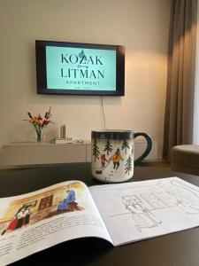 a book and a coffee cup on a table with a tv at Apartmán KOZAK LITMAN in Litmanová