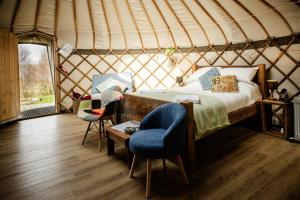 a bedroom in a yurt with a bed and chairs at Kelburn Yurts - Cockle in Fairlie