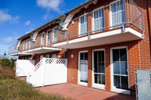 a brick house with a balcony and white doors at Ferienwohnung Kranichglück in Neddesitz
