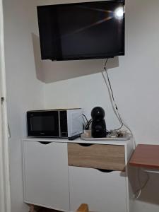 a television hanging on a wall above a microwave at Villaedi in Marina di Bibbona