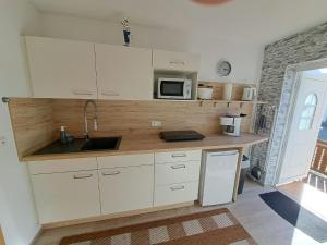 a kitchen with white cabinets and a sink and a microwave at Ferienwohnungen Seestraße in Sassnitz