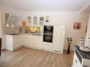 a large white kitchen with white cabinets and appliances at Villa Amelie App Seestern in Sassnitz