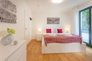a white bedroom with a large bed with red pillows at Villa Friede-Marie App Freya in Sassnitz