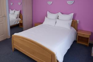 a bedroom with a large white bed with purple walls at Hôtel Restaurant Le Plat d'Etain in Brou