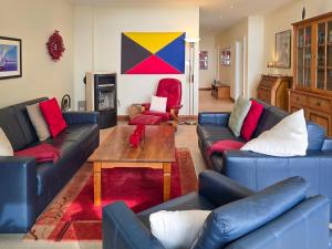 a living room with blue leather couches and a table at Villa Friede-Marie, Penthouse Lenea in Sassnitz