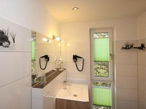 a white bathroom with a sink and a mirror at Villa Amelie FeWo Seemoewe in Sassnitz