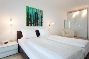 a bedroom with a large white bed and a chair at Villa Friede Marie FeWo Ariane in Sassnitz