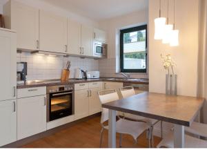 a kitchen with white cabinets and a table with chairs at Villa Friede Marie FeWo Hannah in Sassnitz
