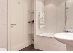 a white bathroom with a sink and a tub at Villa Friede Marie FeWo Hannah in Sassnitz