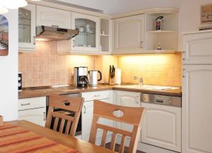 a kitchen with white cabinets and a table and chairs at Villa Friede-Marie, FeWo Meeresidyll in Sassnitz