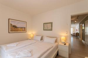 a white bedroom with two beds and two lamps at Villa Friede Marie FeWo Svea in Sassnitz
