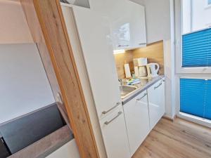 a small kitchen with white cabinets and a sink at Villa Monika Backbord 2 in Sassnitz