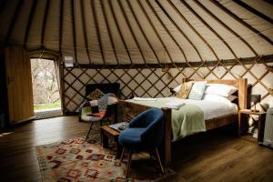 a bedroom in a yurt with a bed and a chair at Kelburn Yurts - Fechan in Fairlie
