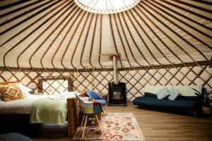 a yurt with a bed and a couch and a chair at Kelburn Yurts - Fechan in Fairlie