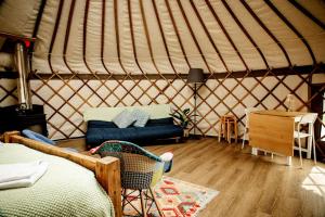 a yurt with a bed and a chair in a room at Kelburn Yurts - Fechan in Fairlie +9 photos