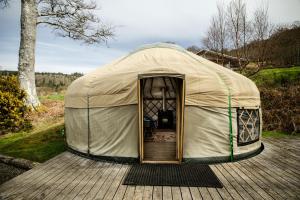 a tent with a door open on a wooden deck at Kelburn Yurts - Fechan in Fairlie