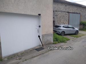 a white garage door with a car parked next to it at Le studio du Sabotier in Oradour-Saint-Genest +2 photos