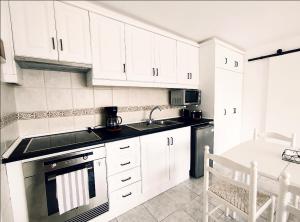 a kitchen with white cabinets and a sink and a stove at La Mar in Los Realejos