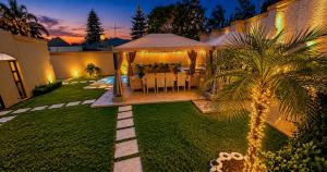 a backyard with a dining area with a tent and a palm tree at Bryanston Palms Accommodation in Johannesburg