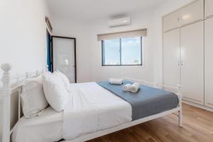 a white bedroom with a bed with two towels on it at Beachside Hideaway Apartment, 200m to the Havana Beach in Pyla