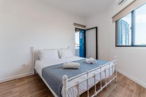 a white bedroom with a bed with two towels on it at Beachside Hideaway Apartment, 200m to the Havana Beach in Pyla