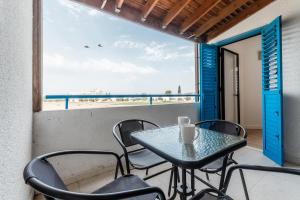 a table and chairs on a balcony with a view of the beach at Beachside Hideaway Apartment, 200m to the Havana Beach in Pyla +11 photos