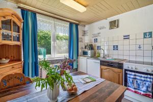 a kitchen with blue curtains and a wooden table at Ferienhof Knudsen in Pellworm