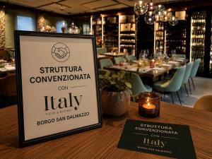 a sign sitting on a table in a restaurant at La Suite Nel Borgo - Ai Piedi delle Alpi&Centro Storico in Borgo San Dalmazzo