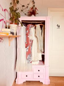 a pink hutch with dresses in it at La Rock House BnB in Mercato Saraceno