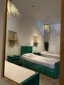 two beds in a room with a mirror at Studio In DaHaB in Dahab
