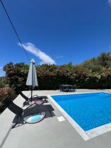 a villa with a swimming pool and an umbrella and chairs at Villa Nicolas Plataria in Plataria