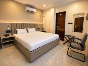 a bedroom with a bed and a chair in it at Kripalu Care Foundation in Vrindāvan +2 photos