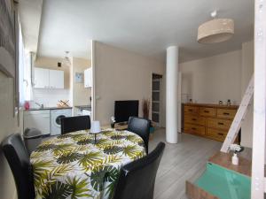 a dining room with a table and chairs and a kitchen at Studio cosy proche plage & centre in Le Havre