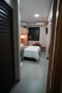 ein Schlafzimmer mit einem weißen Bett und ein Zimmer mit einem Tisch in der Unterkunft Hotel Pandolfi in Dois Vizinhos