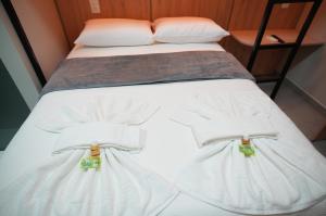 ein Bett mit weißen Laken und Kissen in der Unterkunft Hotel Pandolfi in Dois Vizinhos